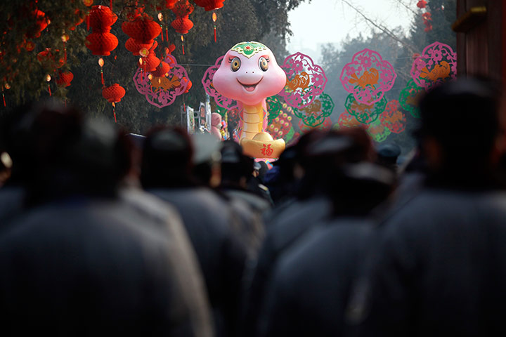 Lunar New Year: Security guards walk towards a snake sculpture in Beijing