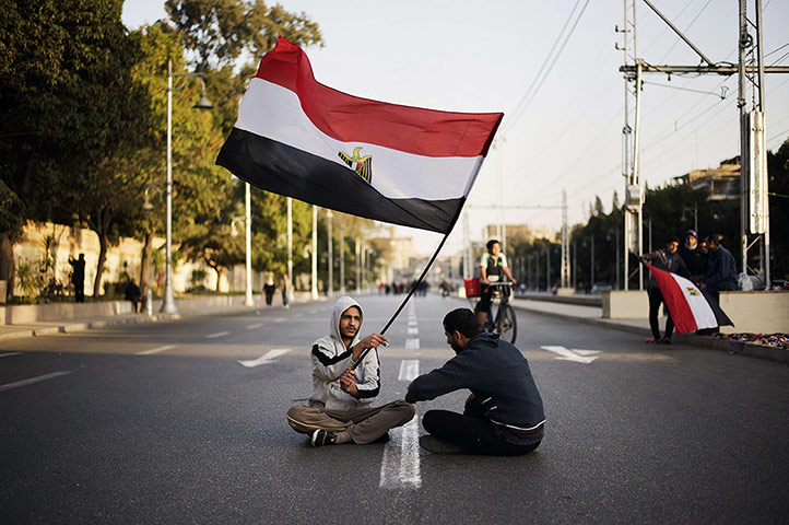 24 hours: Egyptian anti-government protesters sit waving the national flag in Cairo