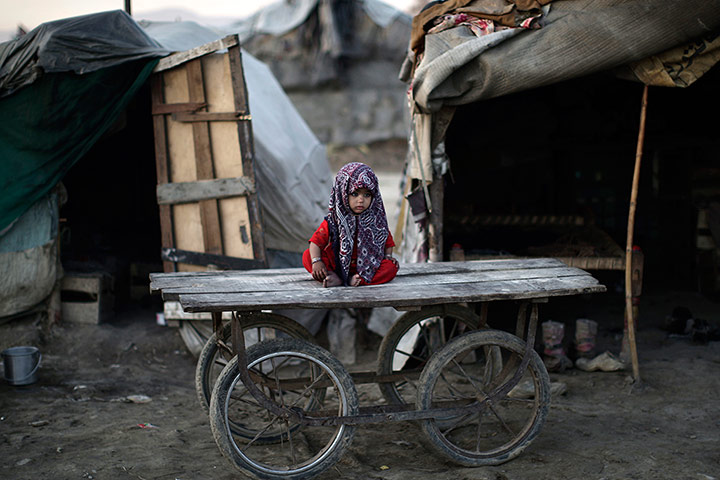 24 hours: A child, whose family was displaced by 2010 floods from a village in Sindh province, sits on a wooden cart outside her family's makeshift home in Islamabad, Pakistan
