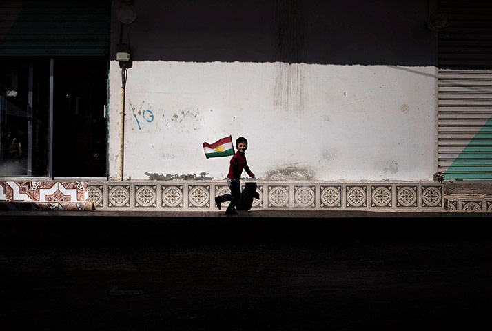 20 Photos: A boy runs as he holds a Kurdish flag in Ras al-Ayn, Syria