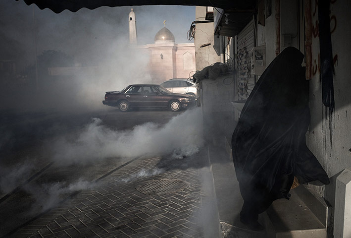 20 Photos: A woman runs from cover for tear gas in Bahrain