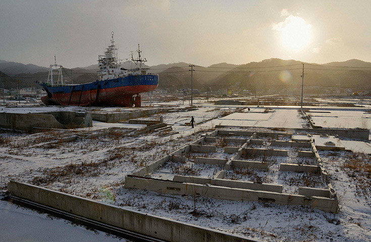 Japan anniversary: A local resident and a dog walk near a ship brought ashore