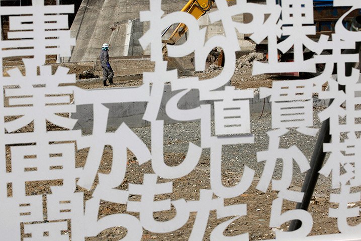 Japan anniversary: A worker walks behind a declaration to reopen a business