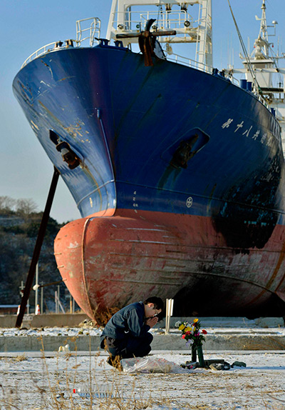 Japan anniversary: A man prays to mourn victims in front of a ship 