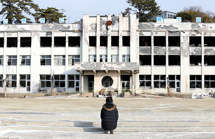 Japan anniversary: A woman prays at the Kadonowaki Elementary School in Ishinomaki, Miyagi