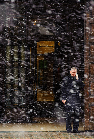 Spring snow: A man shelters from falling snow in a doorway on the Strand, London