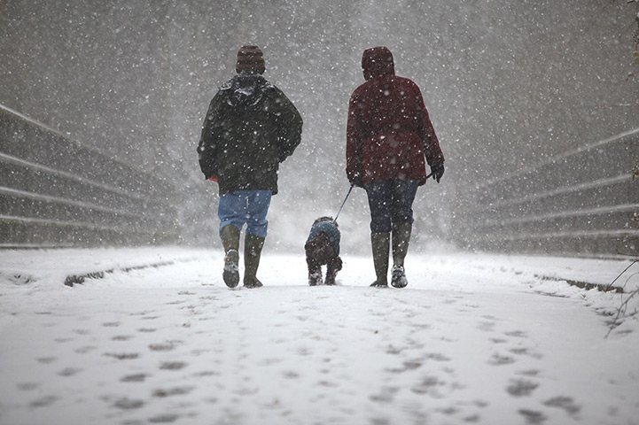 Spring snow: A couple walk their dog in the snow in Crawley, West Sussex