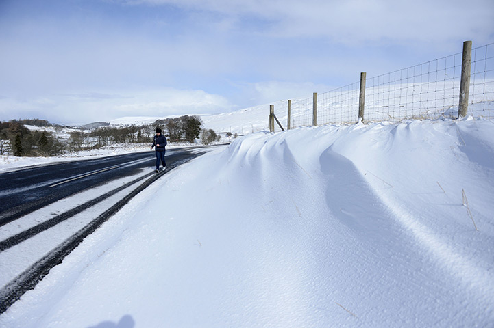 Spring snow: A jogger runs along snowy roads near Allendale Northumberland