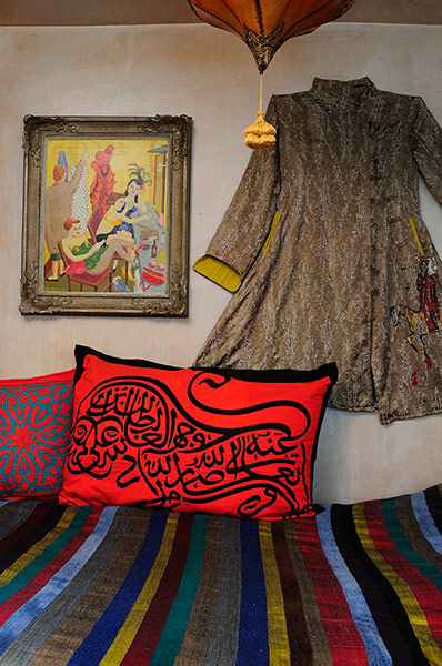 Homes - moroccan home: bed with bright red cushion and moroccan coat 
