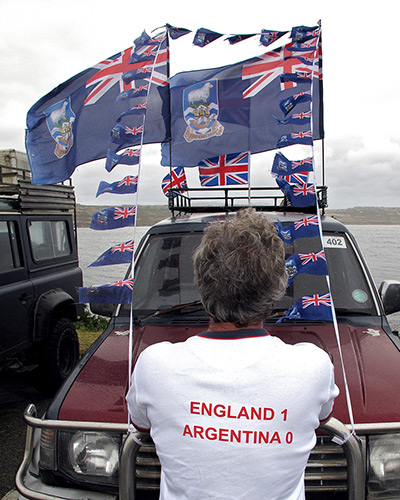 Falkland Islands: A man looks at a vehicle decorated with flags in Stanley