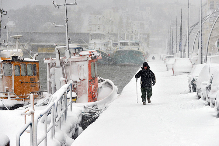 Europe snow: A man walks at the harbour in Cherbourg during heavy snowfall