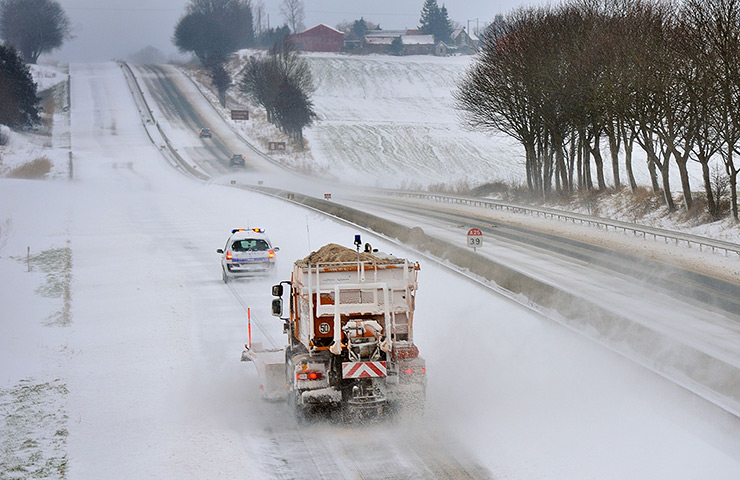 Europe snow: A snowplough follows a police car on the A25 highway in Godewaersvelde