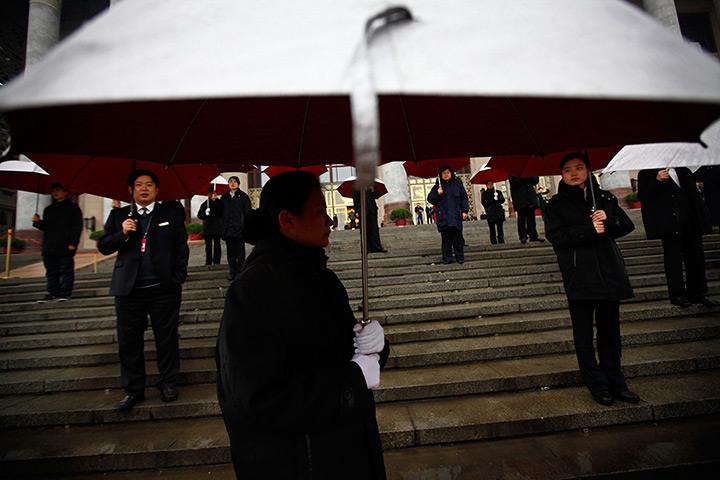 24 hours in pictures: Security personnel holding umbrellas waits for delegates