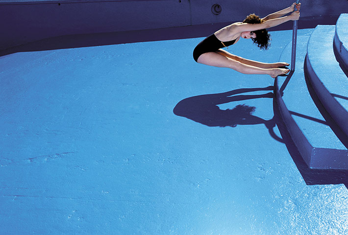 Big Pic - Guy Bourdin: model in empty blue swimming pool wearing black swimsuit