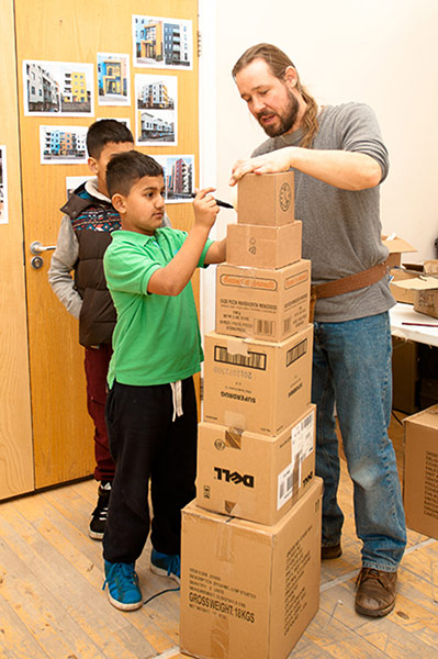 catalyst1: Man helping young child with cardboard tower block