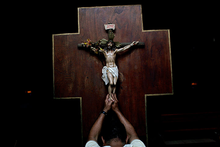 20 Photos: A man prays as he touches a crucifix