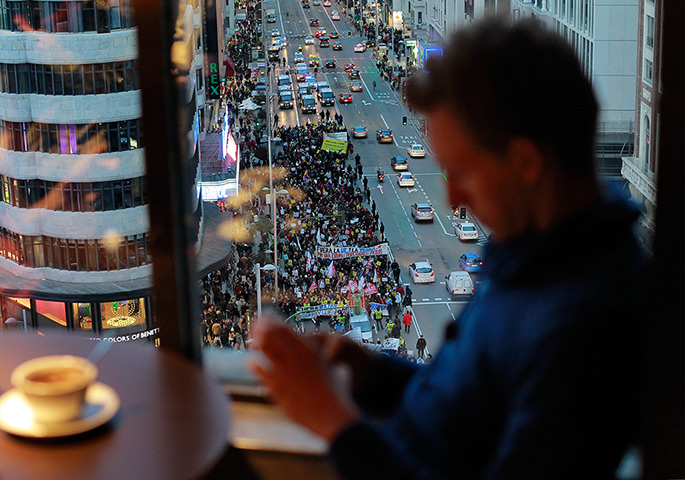 24 hours: Madrid, Spain: a tourist drinks coffee as demonstrators march