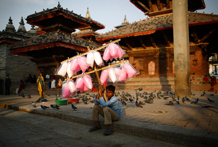 24 hours in pictures: A child sells cotton candy as he waits for customers along the street 