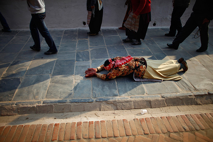 24 hours in pictures: A Buddhist devotee lays in ritual the Boudhanath Stupa 