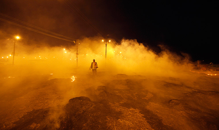 24 hours in pictures:  Indian man walks past burning piles of garbage set afire
