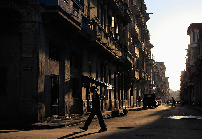 24 hours: Havana, Cuba: People are silhouetted as they walk along a street