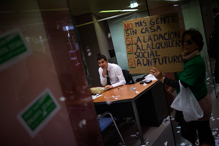 24 hours: Barcelona, Spain: A bank worker watches as activists occupy the bank