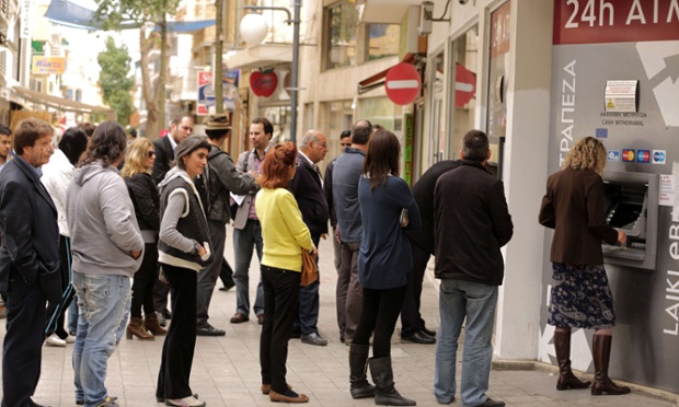 Cypriots and foreigners wait in line to withdraw money from an ATM of a Laiki (Popular) Bank branch in the old city of the capital, Nicosia, on March 21, 2013.