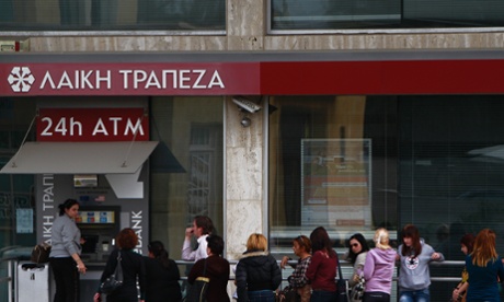 People wait and use the ATM machine of a closed branch of Laiki Bank in capital Nicosia, Thursday, March 21, 2013.