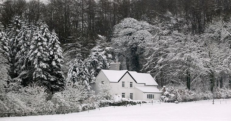 Uk snow update: A white house surrounded by snow covered trees in Mold, North Wales
