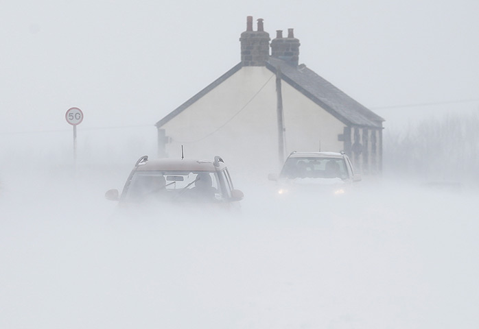 Uk snow update: Motorists drive through snow blown from fields near Buxton