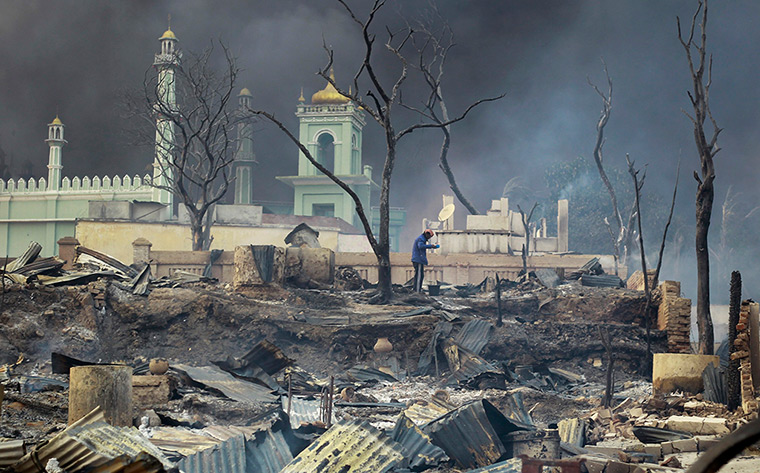 Burma violence: A man stands in front of a mosque as it burns in Meikhtila