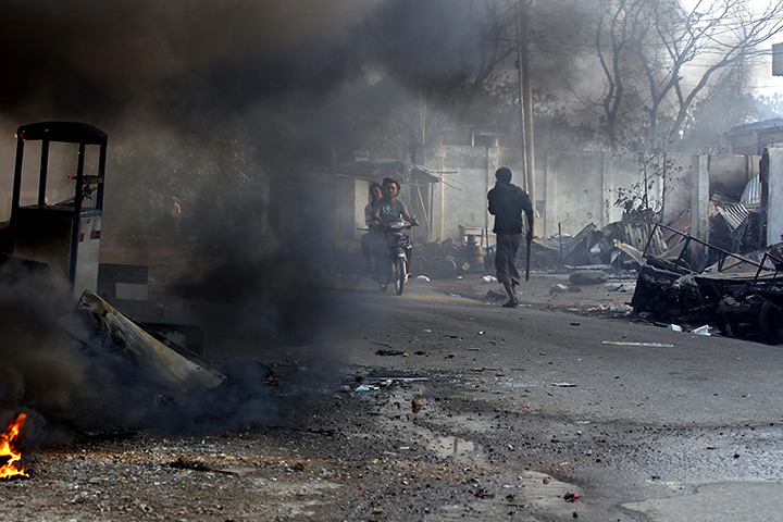 Burma violence: 22 March: A man holding a machete walks through smoke