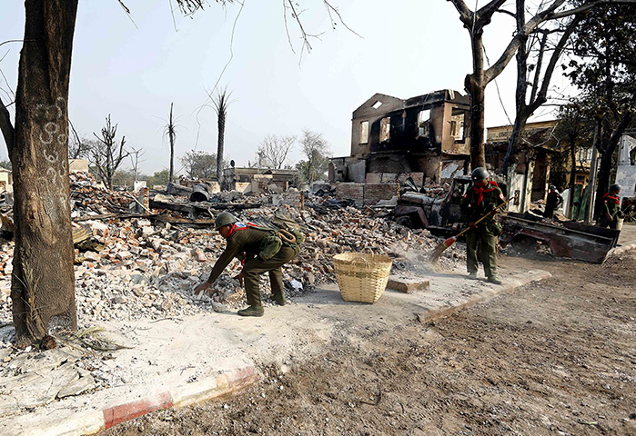 Burma violence: 24 March: Burmese soldiers clear debris after riots