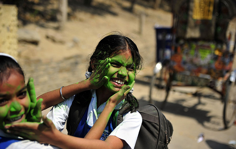 24 hours in pictures : School girls play with coloured powder, India