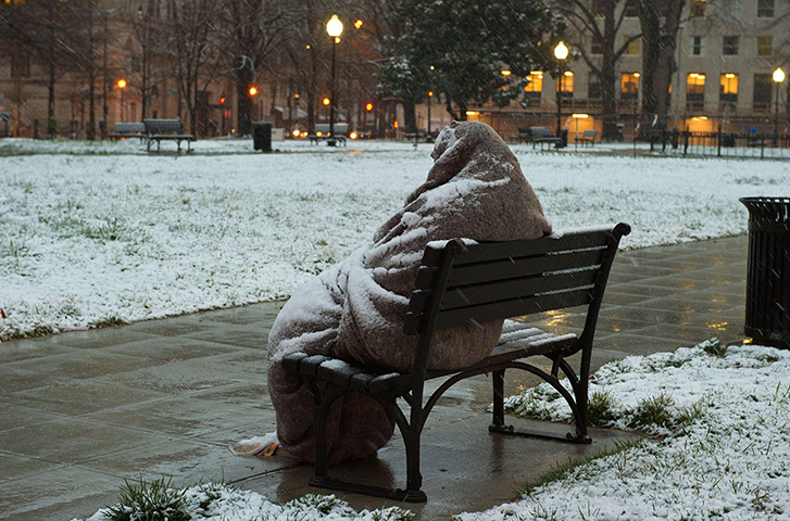 24 hours in pictures: A homeless man sits covered in snow