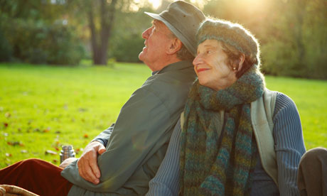 Senior couple sitting side by side in a park. 
