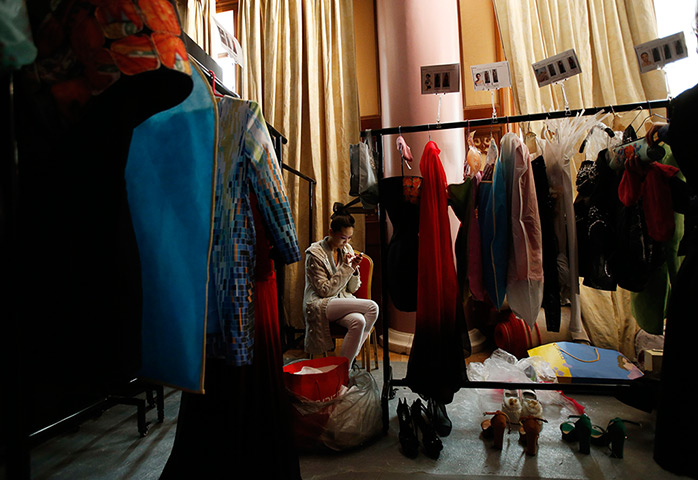 24 hours: Beijing, China: A model uses a mobile phone backstage