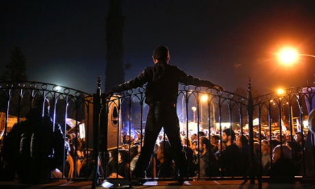 A protester stands atop the fence at the Presidential Palace during an anti-bailout rally in Nicosia March 27, 2013.