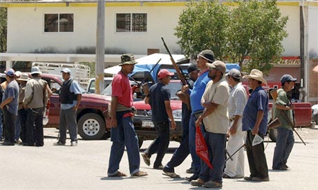 Armed men stand at the entrance to the town of Tierra Colorada, Mexico