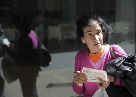 A woman holds cheques outside a closed Laiki bank branch in the old part of the Cypriot capital, Nicosia, on March 28, 2013, ahead of their reopening after an unprecedented 12-day lockdown.