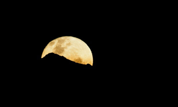 View of a full moon coming out from behind the central Andes in Cali, Colombia.