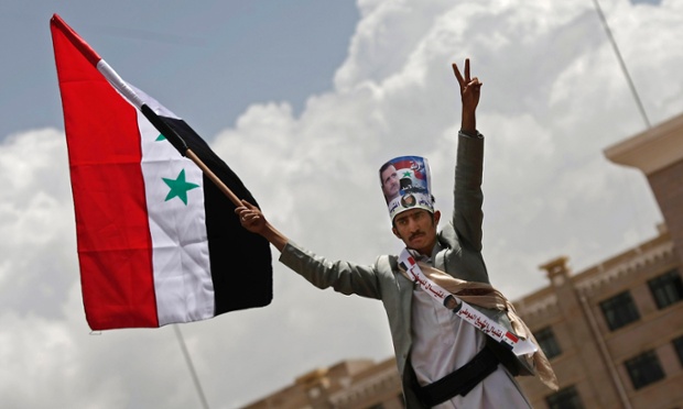 A Yemeni man holds the Syrian flag during a rally in support of President Bashar Assad in Sanaa, Yemen.