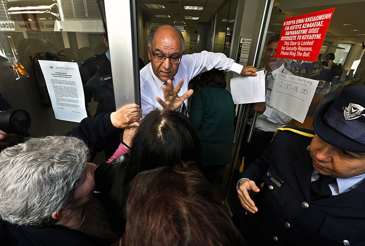 Cyprus banks: A Laiki Bank manager tries to calm depositors waiting for the opening