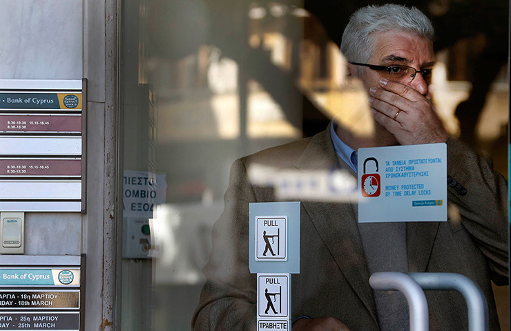Cyprus banks: An employee reacts while looking out at people and reporters