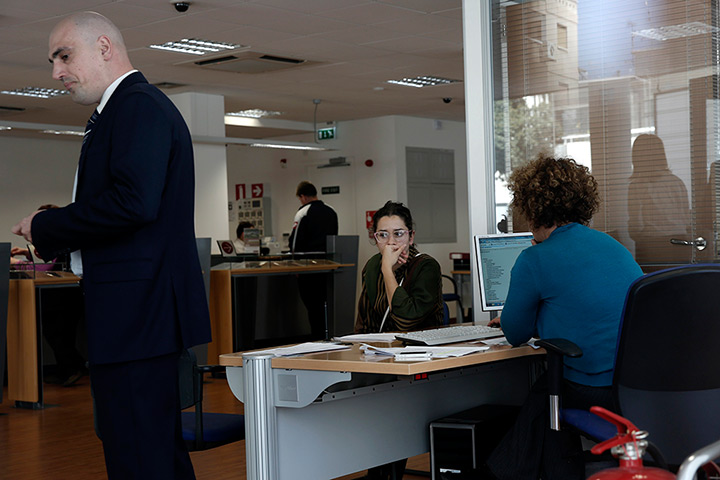Cyprus banks: A customer waits to be served by an employee inside a branch of Laiki Bank