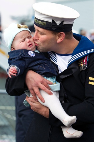 Did you miss me? Leading Seaman Kyle Broomhead from Barnsley doesn't quite get the reaction he'd hoped for as he kisses his daughter six month old Phoebe after returning from deployment aboard HMS Edinburgh, the Navy's last remaining Type 42 destroyer, at the Royal Navy Dockyard in Portsmouth.