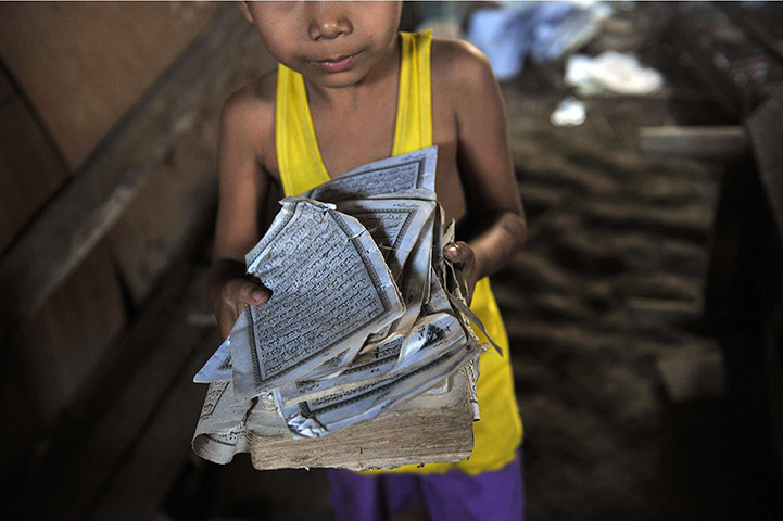 24 hours: Zeegone, Burma: A boy shows the torn pages of a Qu'ran 
