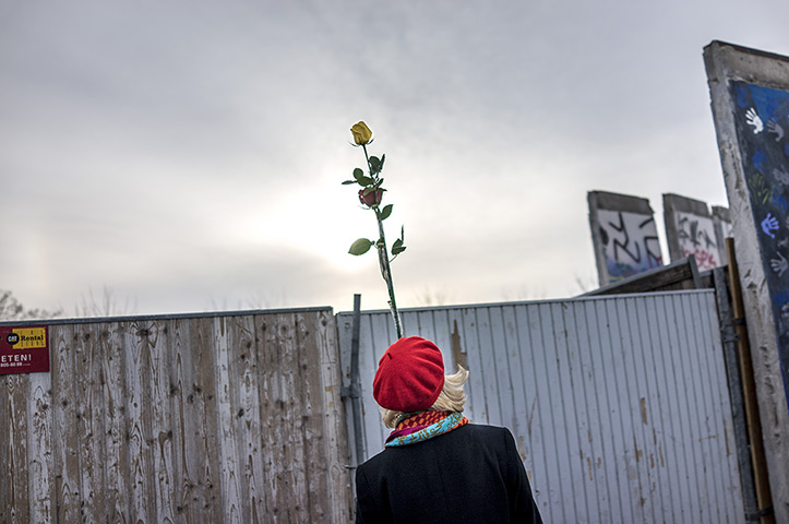 24 hours: Berlin, Germany: A woman holds a rose after a section of the Berlin Wall