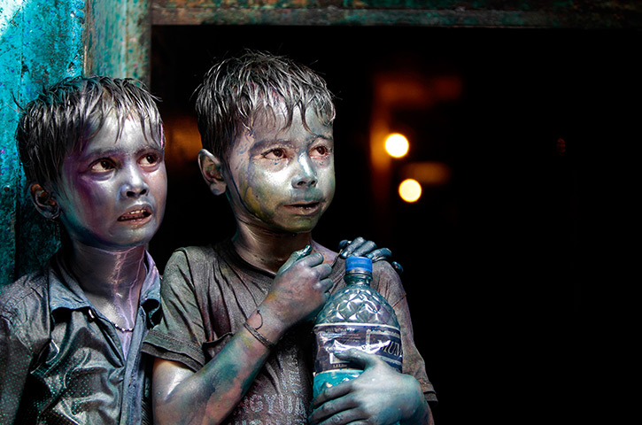 Holi festival: Hindu children smeared in colours stand at a doorway in Dhaka, Bangladesh