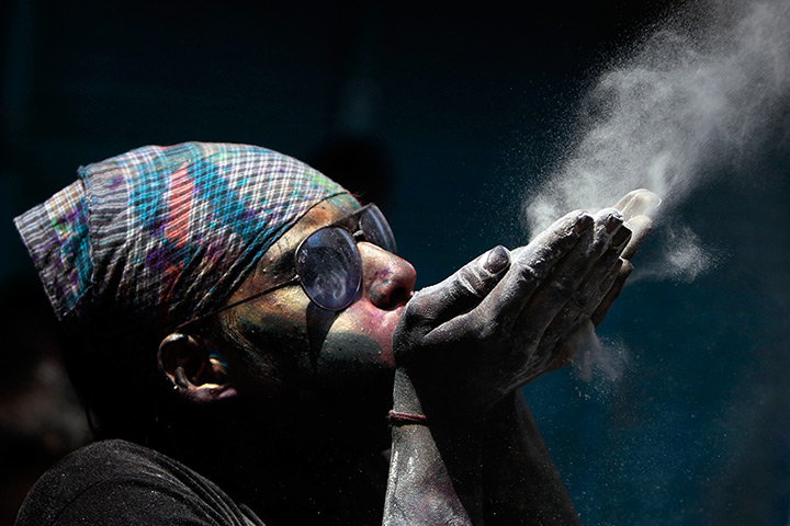 Holi festival: A Hindu man blows coloured powder during Holi festival celebrations